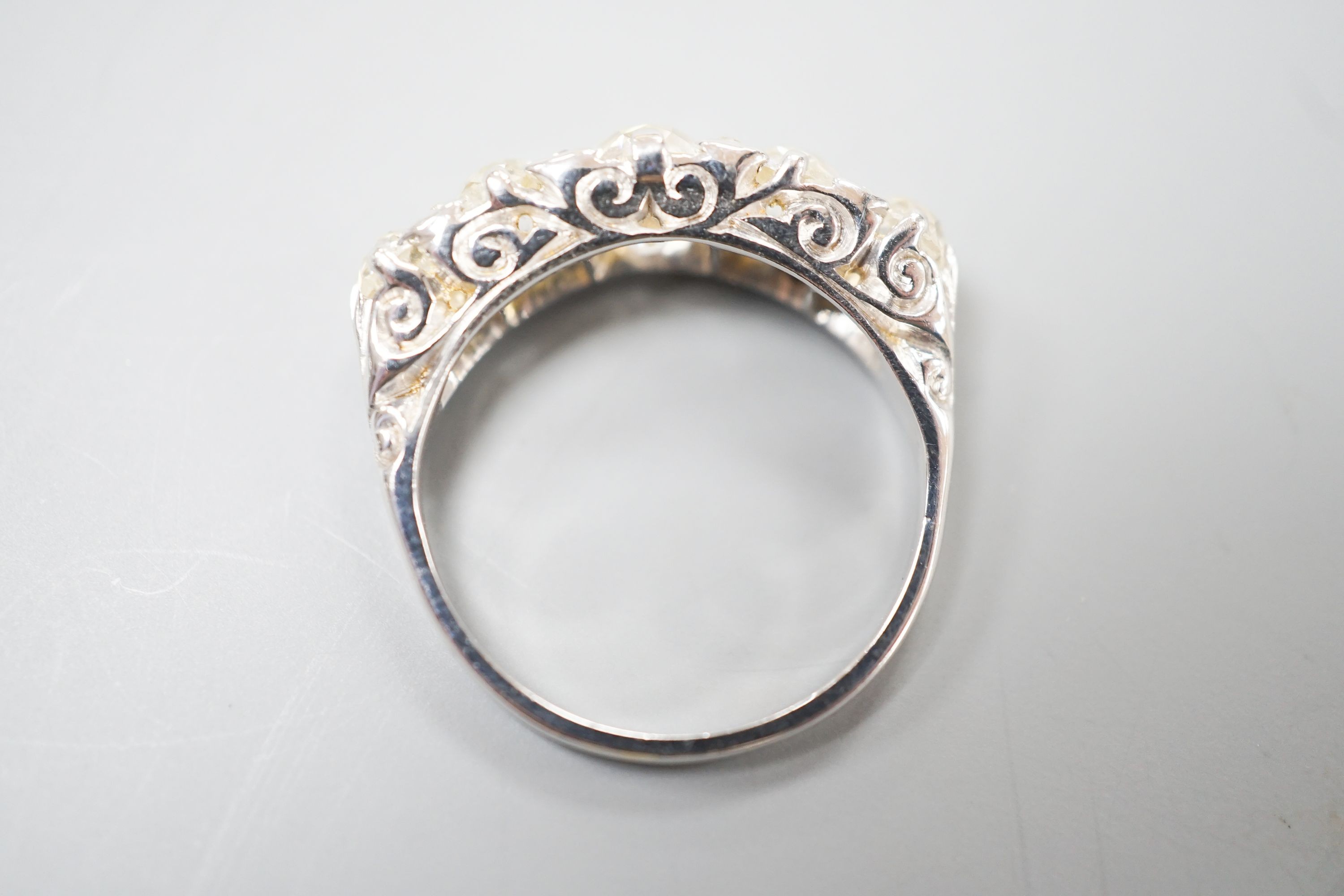 A white metal and graduated five stone old cut diamond set half hoop ring, with diamond chip spacers, size L, gross weight 3.7 grams.